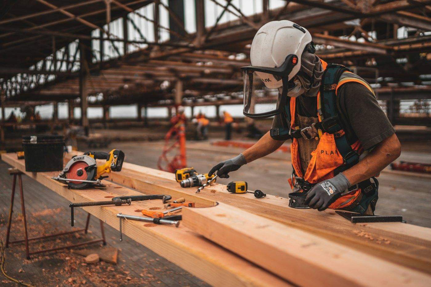 A carpenter in protective gear cutting timber on site