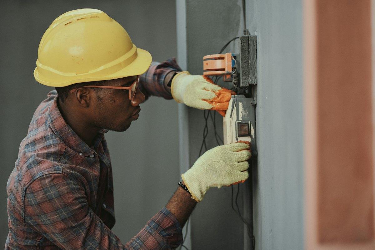 Electrician in a hard hat testing a distribution board