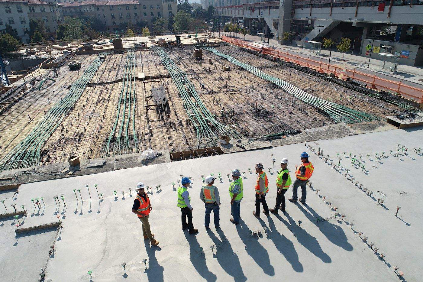 A site team in high-visibility vests walking across a large construction site